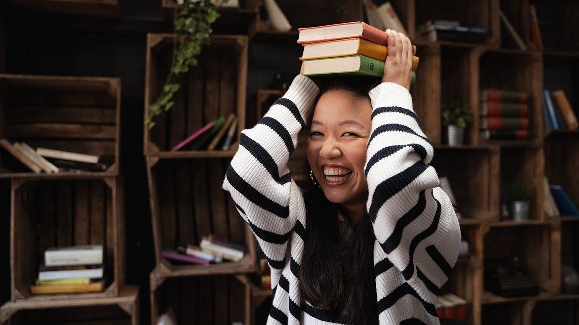 30 procent na wypoczynek i osobiste pragnienia obieta w pasiastym swetrze śmiejąca się i trzymająca książki nad głową