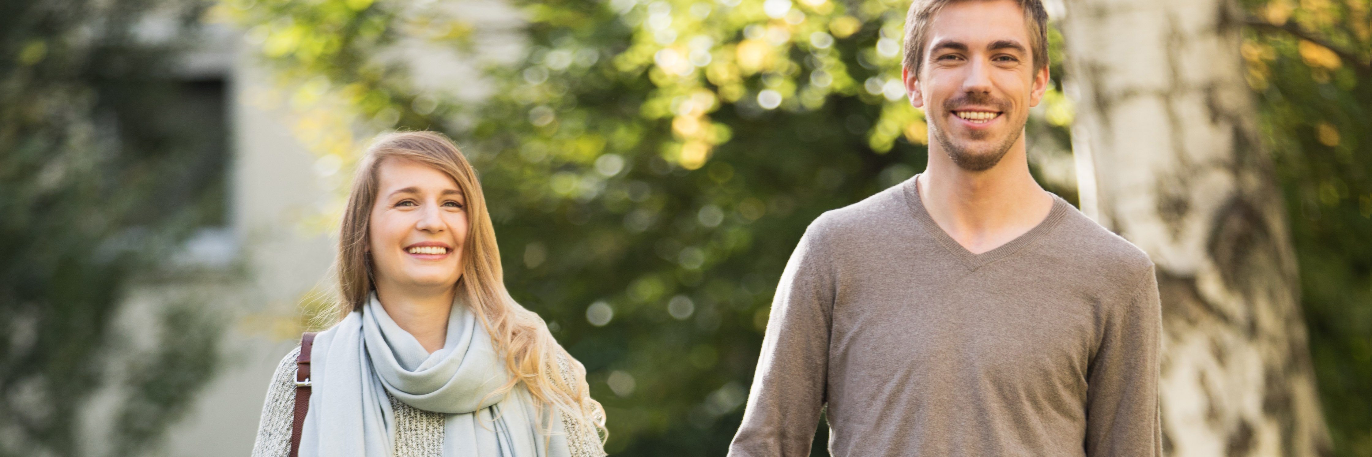 Młoda para uśmiechnięta podczas spaceru w parku Młoda para uśmiechnięta podczas spaceru w parku