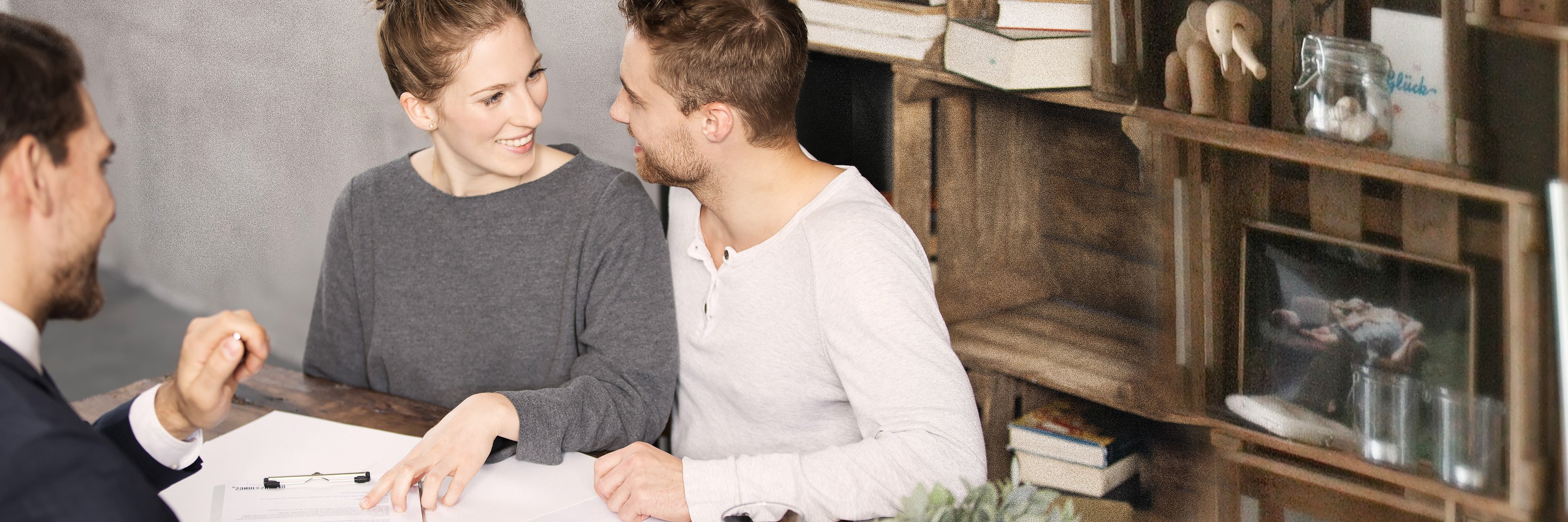 Młoda para siedzi uśmiechnięta u doradcy finansowego. Młoda para siedzi uśmiechnięta u doradcy finansowego.