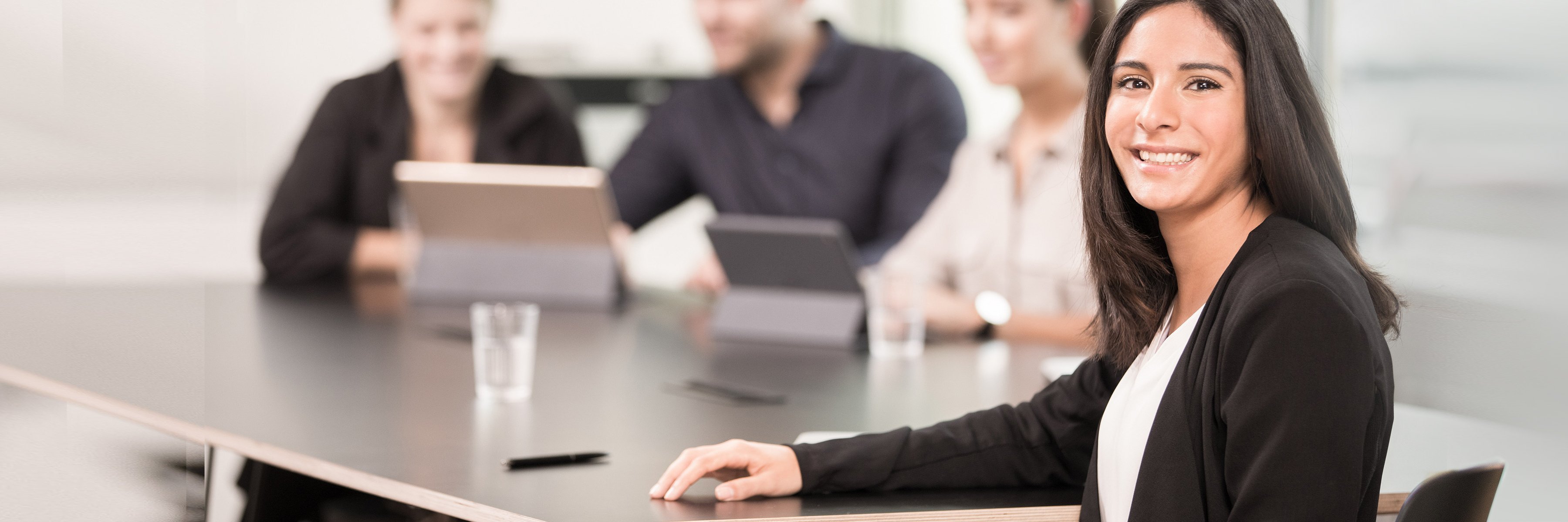 »Właściwe ubezpieczenie zdrowotne to sprawa indywidualna.« Zdjęcie kilku osób w sali konferencyjnej, w centrum uwagi znajduje się kobieta uśmiechająca się do aparatu.